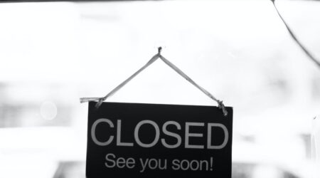 A black and white photo of a closed sign on a glass door