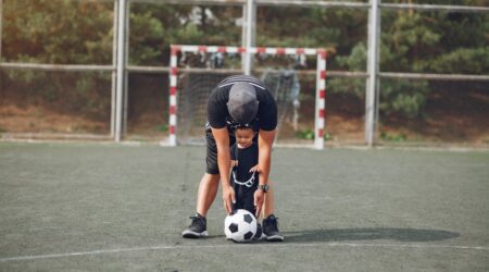 A man teaches a child how to play soccer