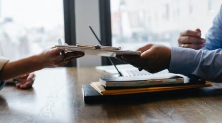 Two professionals pass a clipboard