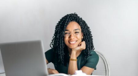 A young woman smiles while sitting at a computer